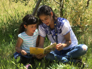 A mother reading to her daughter in LandPaths' iRead Outside program