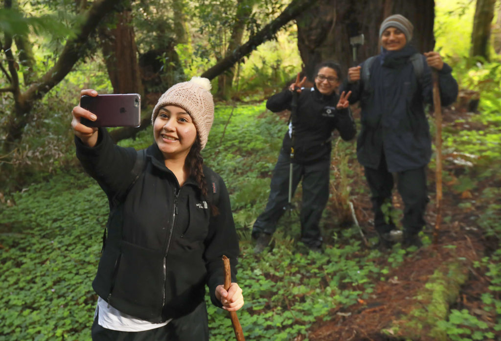 Young woman talking a selfie of her and two friends in the forest