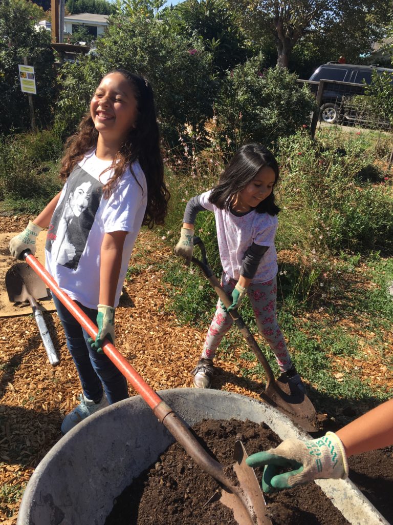 Two girls shoving dirt at Bayer Farm