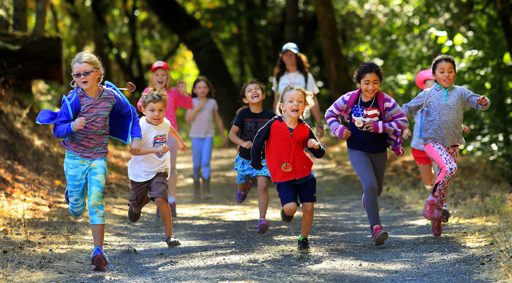Children racing down a gravel path at Owl Camp