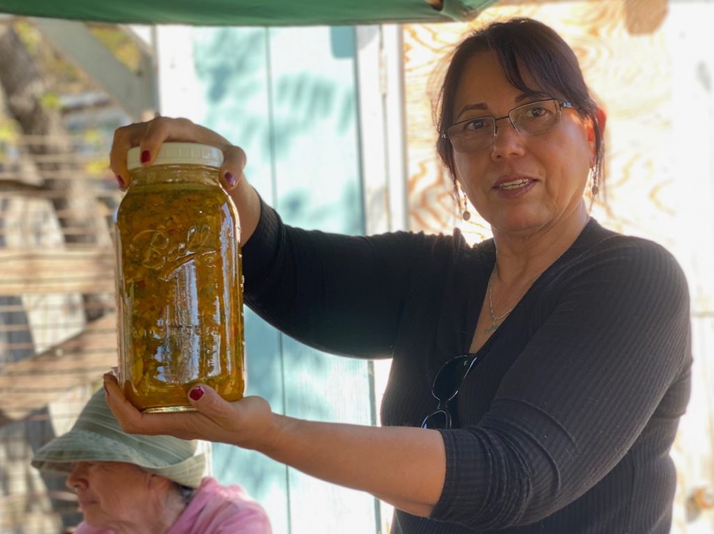 Farming for Health volunteers holds up herbal medicine in a large jar.