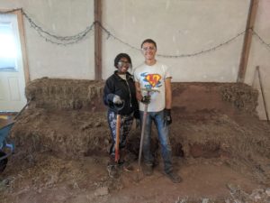 two volunteers at Ocean Song stand with shovels before cob benches