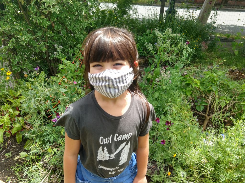 little girl smiling in a face mask and owl camp t-shirt,